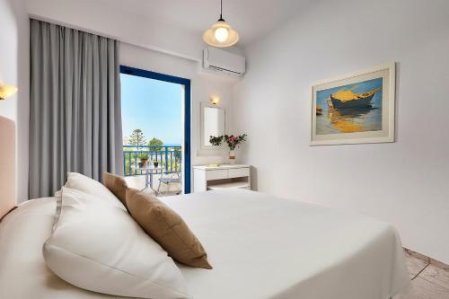 a white bedroom with a bed and a window at Ilios Suites in Kato Gouves