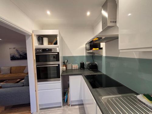 a kitchen with white cabinets and a gray counter top at Seafront Sheringham 1 bed Apt sleeps 4 - 1xdog in Sheringham