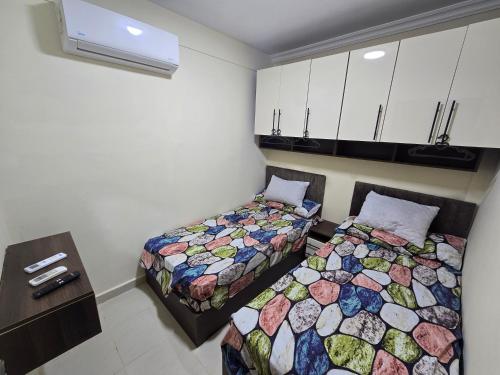 a room with two beds and a table and cabinets at شاليه غرفتين مكيف بورتو جولف مارينا in El Alamein