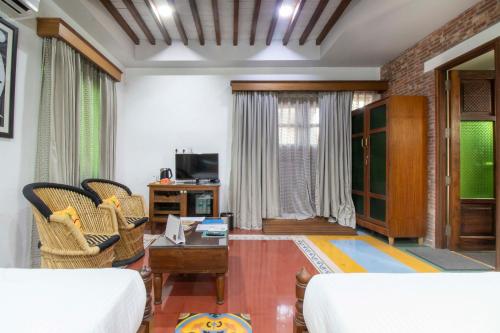 a living room with a couch and chairs and a tv at Namaste Dwaar - The Gateway to Rural India in Khatauli