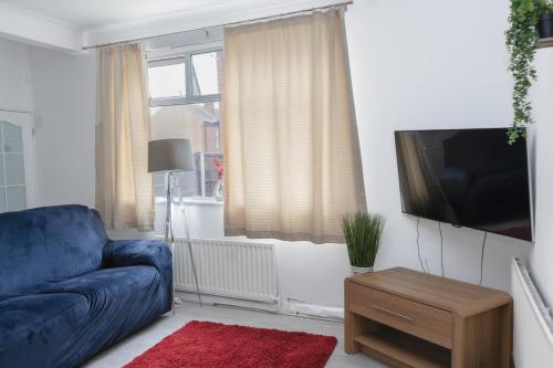 a living room with a blue couch and a tv at Spacious and Comfy Pad - Perfect for Long Stays & Contractors - Close to Sports Village, Leigh Market, and Mesnes Park - Easy Parking - Speedy Wi-Fi - Free On-Site or Nearby Parking - Private Luxury Garden in Leigh