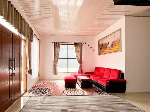a living room with a red couch and a window at Labella Homestay 2 Syariah RedPartner near 0 KM Dieng in Dieng