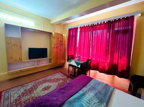 a bedroom with a bed and a tv and red curtains at Hotel Nirvana in Vashisht