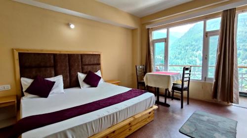 a bedroom with a bed and a table and window at Hotel Nirvana in Vashisht