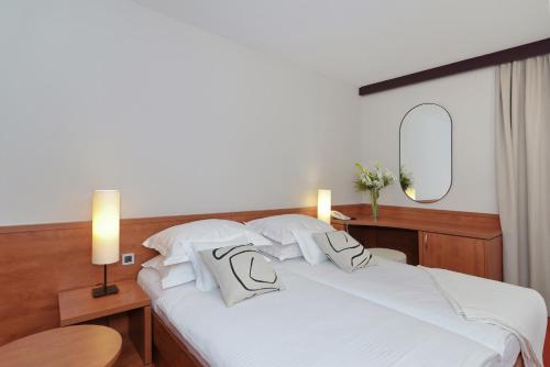 a bedroom with a white bed with two pillows at Hotel Villa Donat in Sveti Filip i Jakov