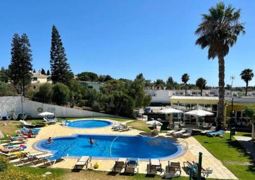 una grande piscina con sedie e palme di Casa Zen Apartamentos Santa Teresinha Montes de Alvor ad Alvor