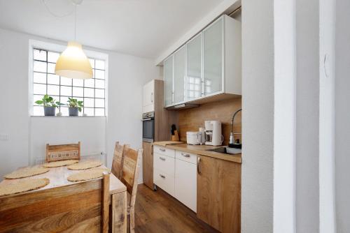 a kitchen with white cabinets and a wooden table at Apartmenthaus Schlosspark in Worms