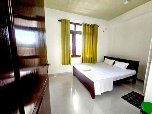 a bedroom with a bed and a window with yellow curtains at Sea Breeze Guest House Negombo in Negombo