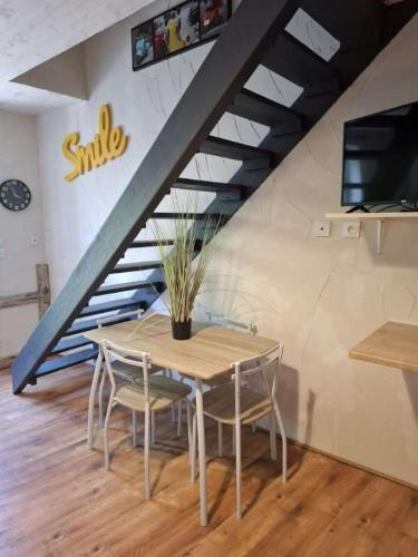 une table et des chaises dans une pièce avec un escalier dans l'établissement le nid des choups le petit duplex 2 personnes, à La Bourboule