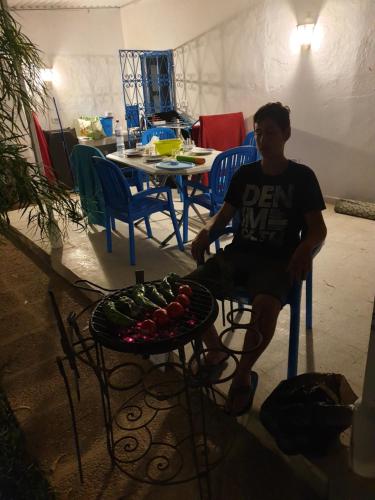 a man sitting in a chair next to a table with vegetables at Chelly Bungalow en bord de mer in Nabeul