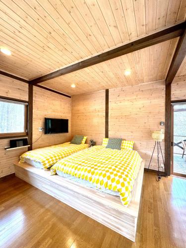a bedroom with two beds and a television in it at Second House ホッポッタ in Kita-karuizawa