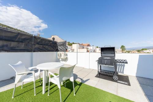 a patio with a table and a grill on a roof at La Casa de la Buhardilla in Fondón