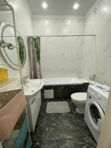 a bathroom with a sink toilet and a washing machine at Sat City block A in Astana