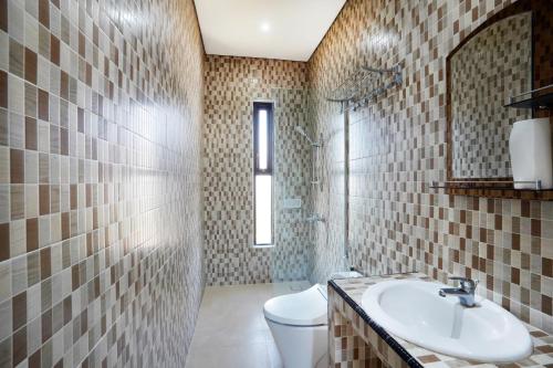 a bathroom with a sink and a toilet and a mirror at Mahabrahma Villa in Uluwatu
