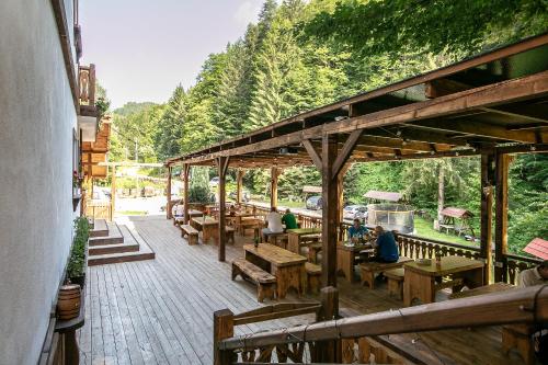 a wooden deck with benches and tables and trees at Transfagarasan Moto&Cabin Camp in Văleni