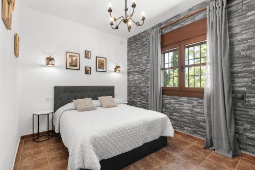 a bedroom with a bed and a brick wall at Cortijo Era del Realenguillo in Villanueva de la Concepción