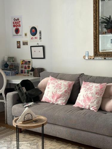 - un salon avec un canapé gris et des oreillers roses dans l'établissement Elegant Flat in Marais Paris, à Paris