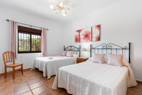 a bedroom with two beds and a chair and a window at El Mirador del Abuelo in Málaga