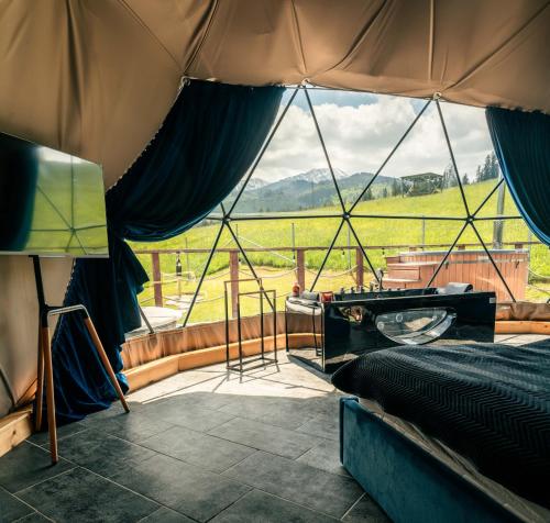 a bedroom with a tent with a view of a field at Góralski Harem Osada Glamp & Glass z Jacuzzi i Balią in Zakopane