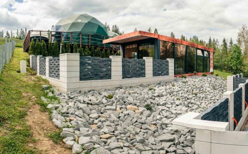 a building with a pile of rocks in front of a building at Góralski Harem Osada Glamp & Glass z Jacuzzi i Balią in Zakopane