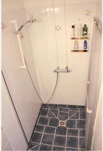 une douche avec un sol carrelé noir dans une salle de bain dans l'établissement Appartement Spacieux au cœur du GRAU, au Grau-du-Roi