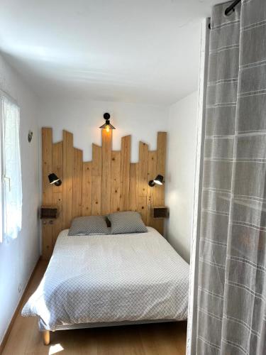 une chambre avec un grand lit avec une tête de lit en bois dans l'établissement Appartement Spacieux au cœur du GRAU, au Grau-du-Roi