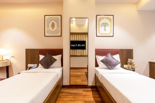 two beds in a room with a mirror at Saltstayz Premier Suite Chandigarh Mohali in Sohāna
