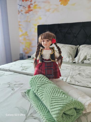 a doll is sitting on top of a bed at Apartman Milja in Požega