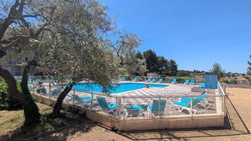 une piscine avec des chaises bleues et un arbre dans l'établissement Harmonie des Thermes, à Balaruc-les-Bains