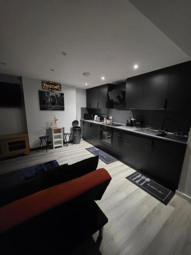 a kitchen with black cabinets and a wooden floor at Tranquil & Subtle - 8ight Havens Folkestone in Folkestone