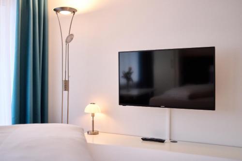 a flat screen tv on a white wall in a bedroom at Huber Living in Germering