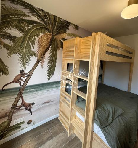 - une chambre avec des lits superposés et une fresque murale de palmiers dans l'établissement mazet duplex terrasses plein sud residence avec piscine, à Aigue-Belle