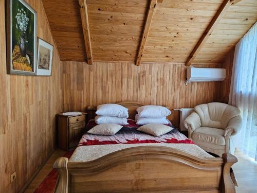 a bedroom with a bed with pillows and a chair at Upeslīči atpūtai in Jelgava