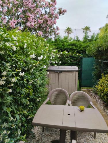 - une table et deux chaises dans un jardin fleuri dans l'établissement Studio Jardin Argelès plage, à Argelès-sur-Mer