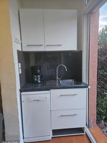 une petite cuisine blanche avec évier et cuisinière dans l'établissement Studio Jardin Argelès plage, à Argelès-sur-Mer