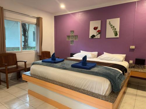 a bedroom with two beds and a purple wall at Lanta Island Resort in Ko Lanta