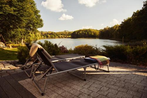 a reclining chaise lounger next to a lake at Domki na Kaszubach - nad jeziorem z balią i sauną in Bytów