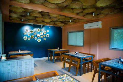 a restaurant with tables and chairs and a blue wall at Bhumiputra stays in Pernem