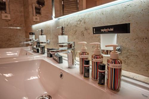 a bathroom sink with several bottles on it at Zep Promenade Spa Apartment in Vrnjačka Banja