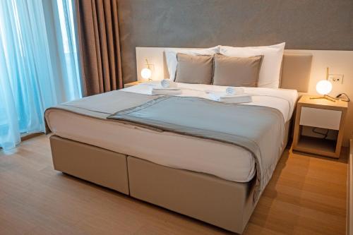 a bedroom with a large bed with two lamps on it at Zep Promenade Spa Apartment in Vrnjačka Banja