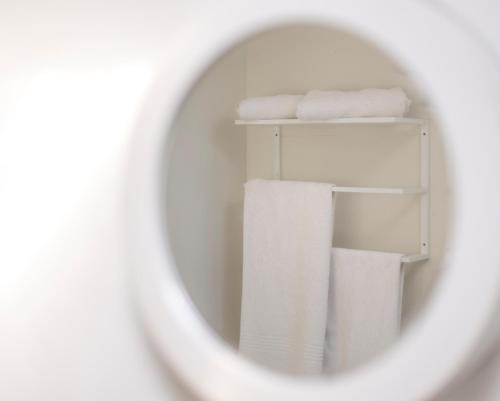 a stack of white towels in a bathroom mirror at Widdy's Beach Club in Widenham
