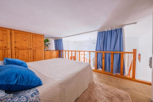 a bedroom with a bed with blue pillows and a balcony at Cafio's house in Lipari