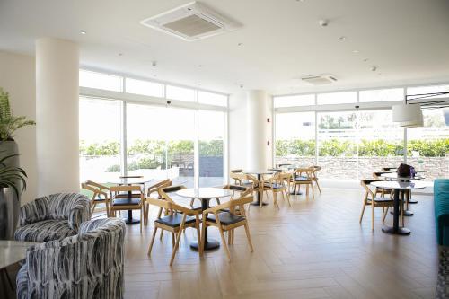 a restaurant with tables and chairs and windows at Soleil La Vie at Azure North Resort Residences in Lagundi