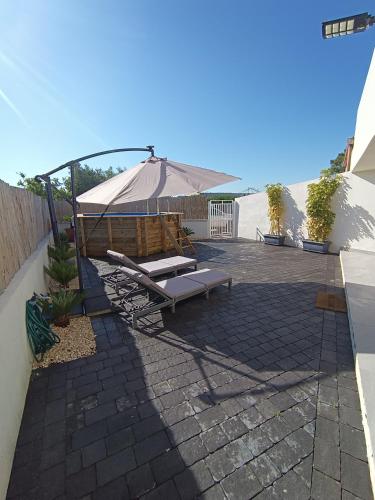 a patio with an umbrella and a chaise lounge at I Coralli di Brucoli in Brucoli