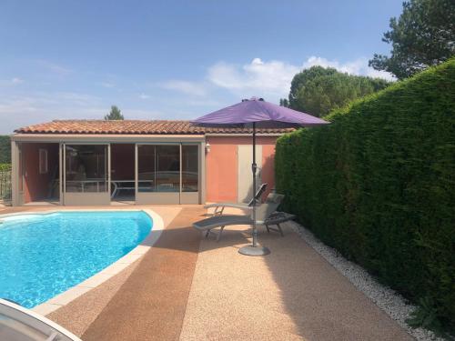 un parasol et une chaise à côté de la piscine dans l'établissement VILLA AVEC PISCINE, à Roussillon