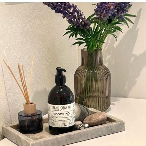 a vase with a bottle of soap and a vase with flowers at FF1004 Autentisk sommerhus ved Hvidbjerg strand in Børkop