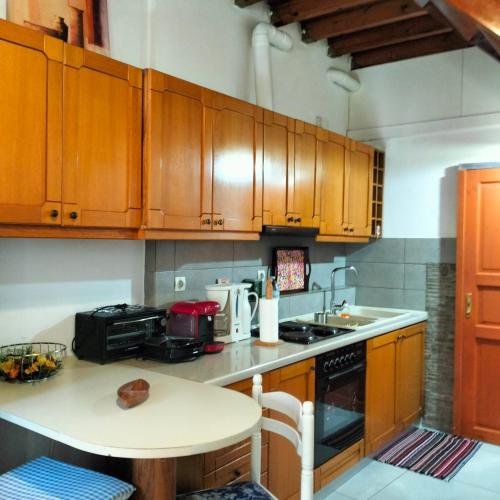a kitchen with wooden cabinets and a table and a sink at Agios Dimitrios House in Plomarion