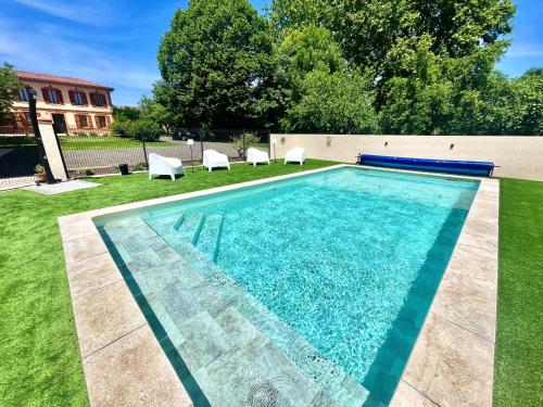 a swimming pool in a yard with white chairs at " Ô Chai Nous " 14 pers - Billard, Babyfoot - Structure de Jeux in Poucharramet