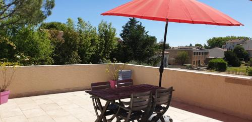 a wooden table and chairs with a red umbrella at Villa Solary in Le Pontet