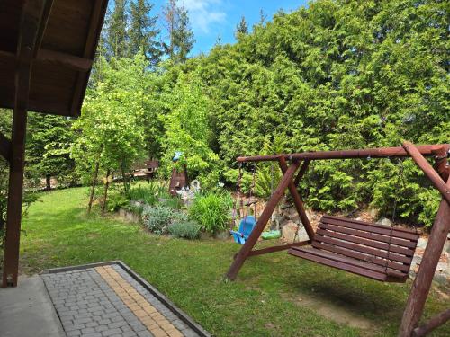 a wooden bench in a yard with a garden at Kamila in Szczawnica